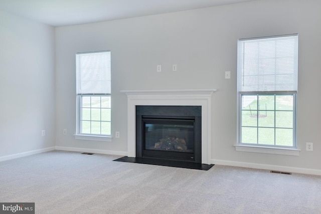 unfurnished living room featuring light carpet and a wealth of natural light