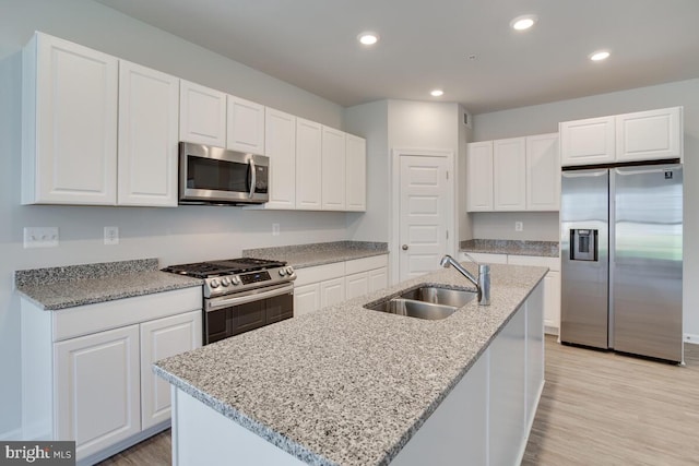 kitchen featuring stainless steel appliances, a kitchen island with sink, sink, and white cabinetry