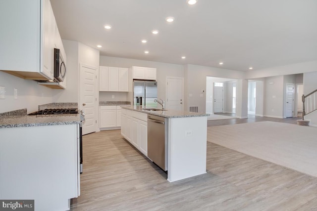 kitchen featuring an island with sink, appliances with stainless steel finishes, and white cabinetry