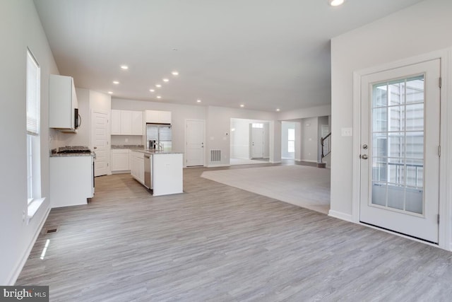 kitchen featuring stainless steel appliances, light wood-type flooring, white cabinets, and a center island