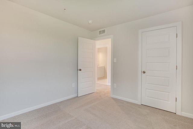 unfurnished bedroom with a closet and light colored carpet