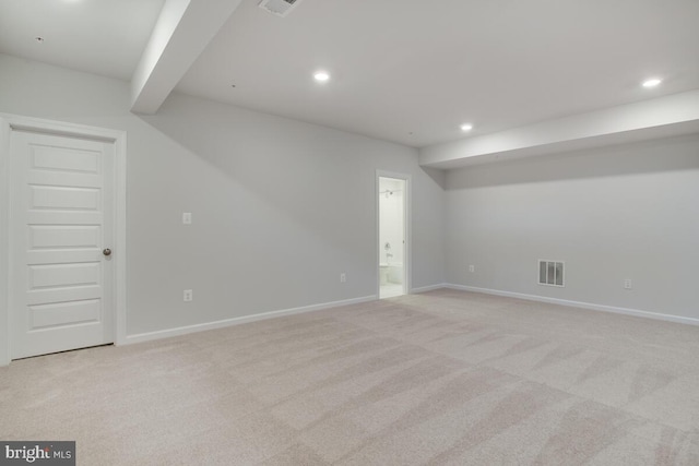 spare room featuring light colored carpet and beam ceiling