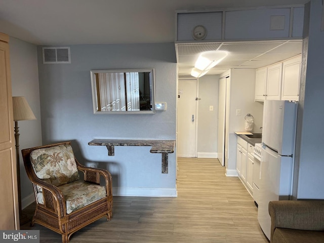 kitchen featuring light hardwood / wood-style floors, white cabinetry, and white fridge