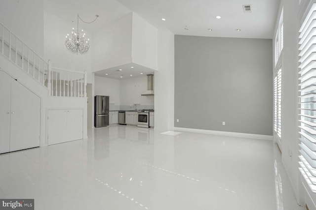 unfurnished living room with a towering ceiling and an inviting chandelier