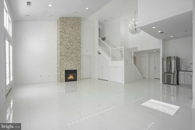 tiled living room with a notable chandelier, a fireplace, and a towering ceiling