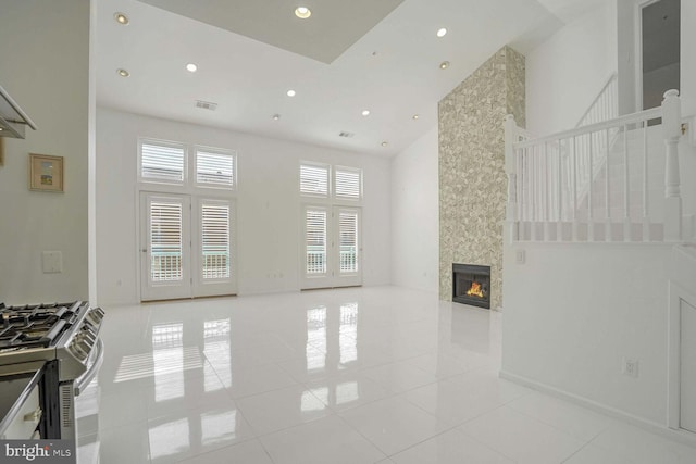 tiled living room featuring a large fireplace and a high ceiling