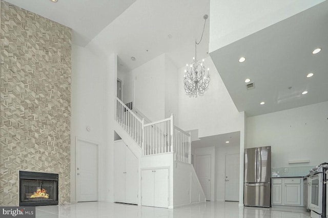 staircase with tile patterned floors, a high ceiling, a notable chandelier, and a tile fireplace