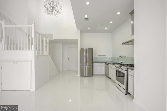 kitchen with sink, white cabinetry, stainless steel appliances, light tile patterned floors, and an inviting chandelier