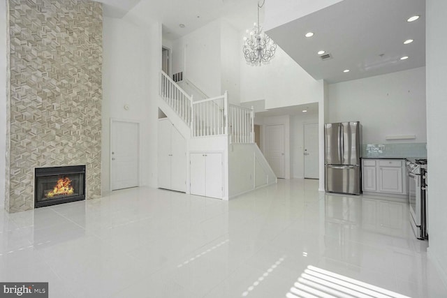 unfurnished living room featuring a high ceiling, a fireplace, an inviting chandelier, and light tile patterned floors