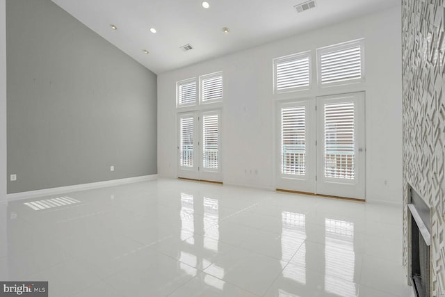 empty room featuring high vaulted ceiling and light tile patterned floors