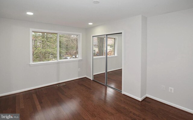 unfurnished bedroom with dark wood-type flooring and a closet