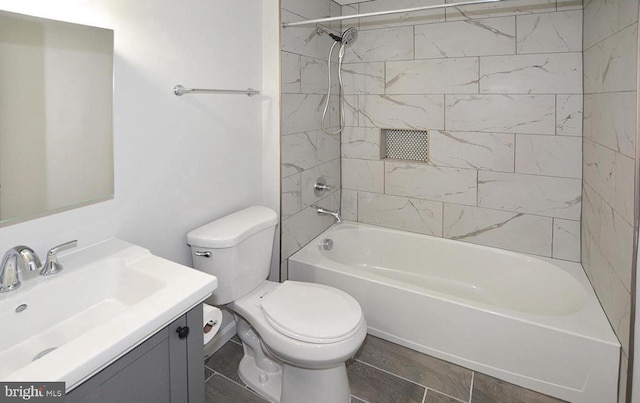 full bathroom featuring toilet, tiled shower / bath combo, vanity, and tile patterned flooring