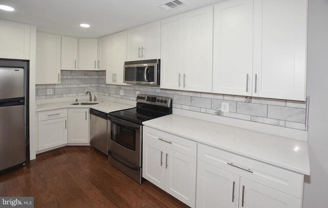 kitchen with dark wood-type flooring, appliances with stainless steel finishes, sink, and white cabinets