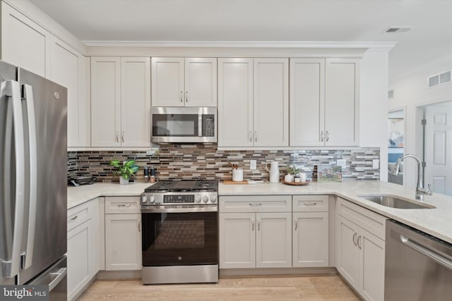 16444 River View Dr, Bristol, PA 19007 - kitchen with stainless steel appliances, a sink, tasteful backsplash, ornamental molding, and light wood-type flooring