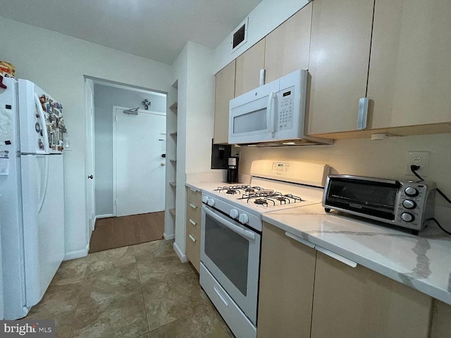 kitchen featuring light stone countertops and white appliances