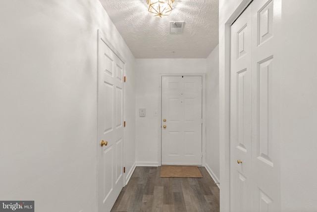 doorway to outside with dark wood-type flooring and a textured ceiling