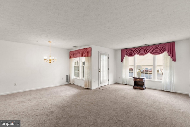 unfurnished living room with a notable chandelier, a textured ceiling, and carpet