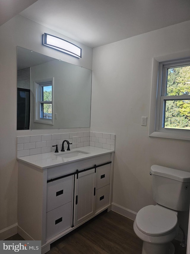 bathroom featuring decorative backsplash, wood-type flooring, vanity, and toilet