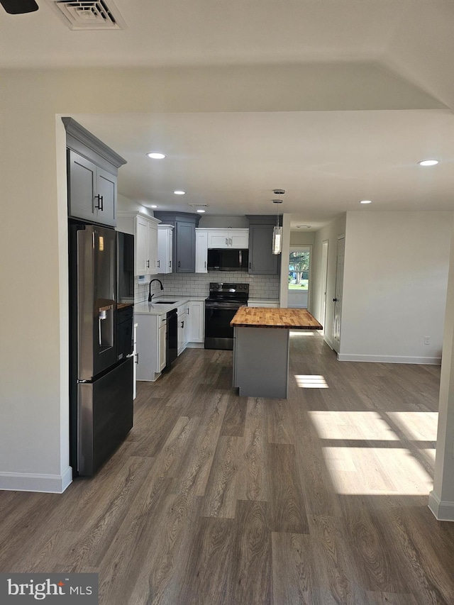 kitchen with butcher block counters, sink, dark hardwood / wood-style flooring, gray cabinets, and black appliances