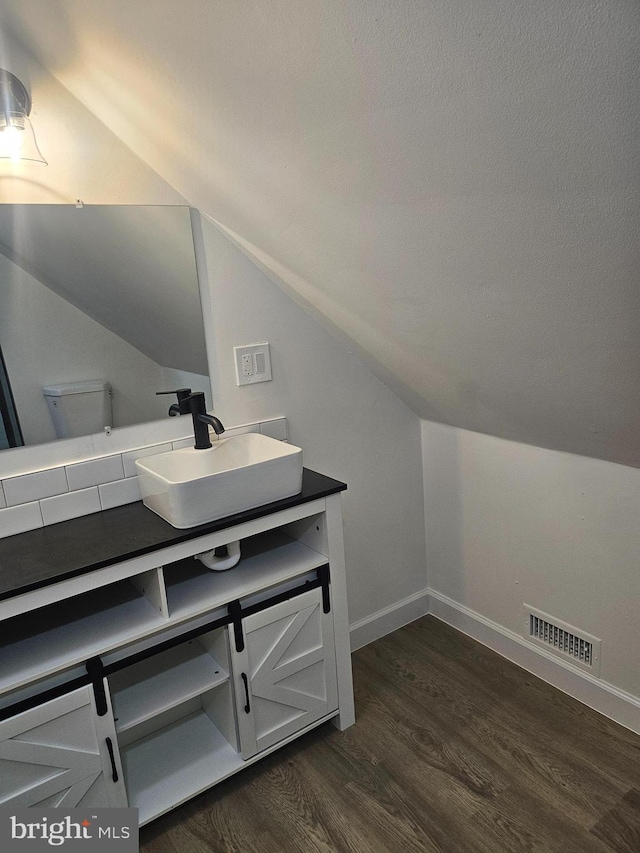 bathroom featuring toilet, vanity, hardwood / wood-style flooring, and vaulted ceiling