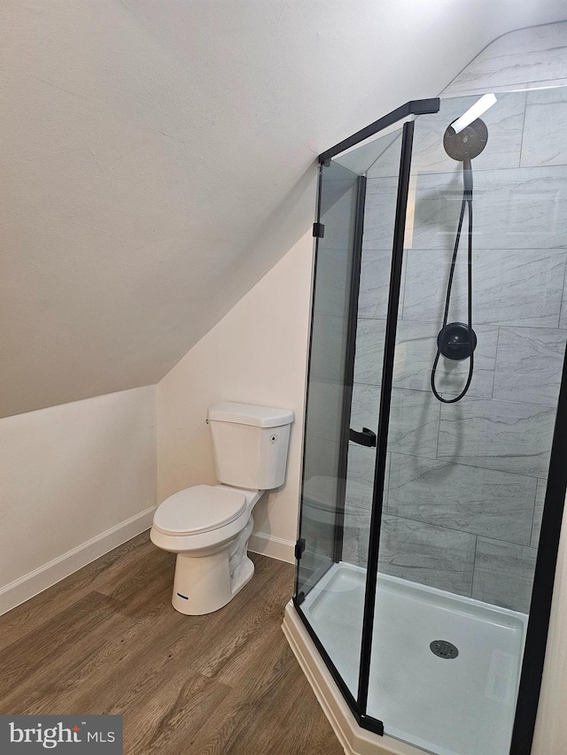 bathroom with vaulted ceiling, wood-type flooring, a shower with shower door, and toilet