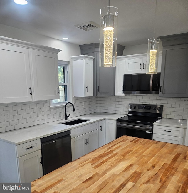 kitchen with white cabinetry, pendant lighting, black appliances, and sink