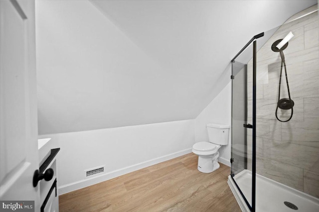 bathroom featuring lofted ceiling, toilet, wood-type flooring, and a shower with door