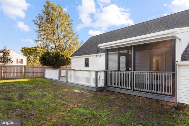 back of house with a sunroom, a deck, and a yard