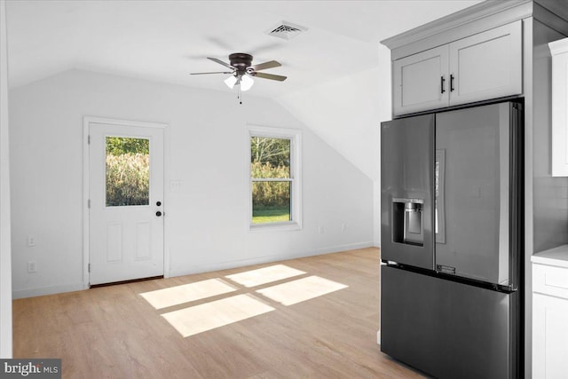 kitchen with plenty of natural light, stainless steel fridge, light wood-type flooring, and lofted ceiling