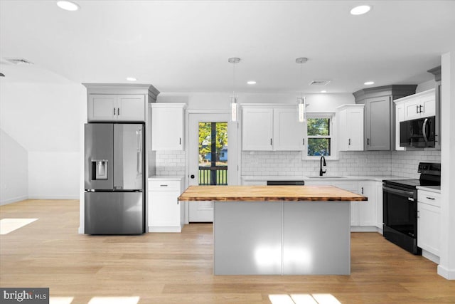 kitchen featuring stainless steel fridge with ice dispenser, electric range, plenty of natural light, and butcher block counters