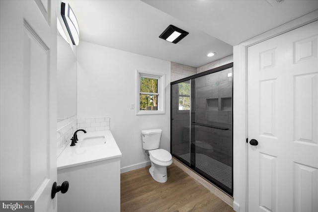 bathroom featuring vanity, wood-type flooring, a shower with shower door, and toilet