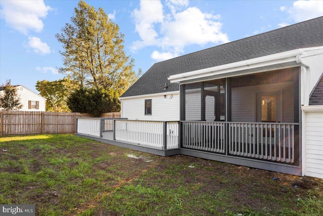 rear view of house with a sunroom, a deck, and a lawn