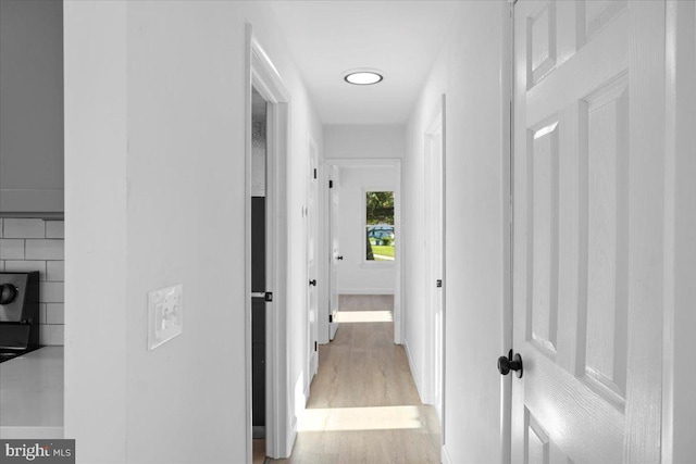 corridor featuring tile walls and light hardwood / wood-style flooring