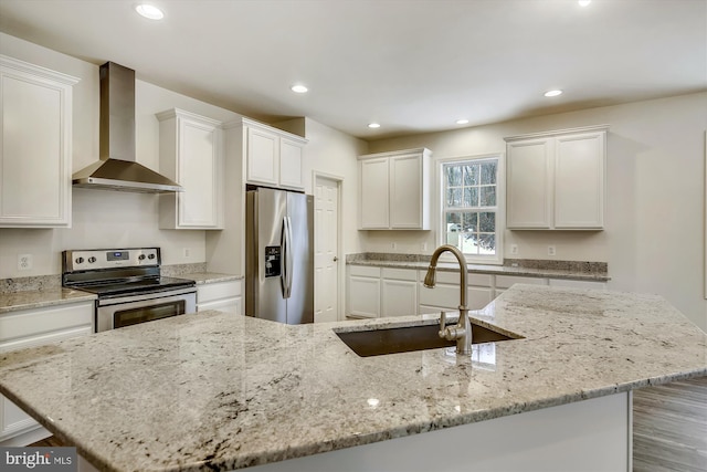 kitchen with light stone counters, stainless steel appliances, sink, and wall chimney range hood