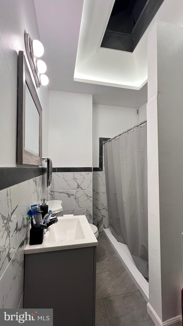 bathroom with toilet, vanity, tile walls, and a shower with shower curtain