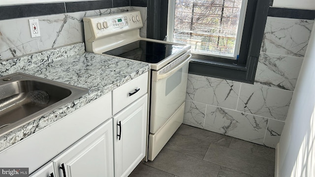 kitchen featuring white cabinetry, tile walls, sink, and white range with electric stovetop