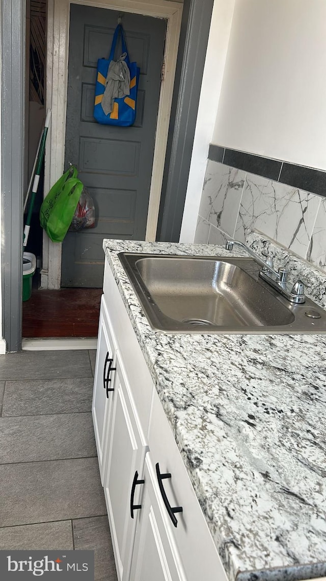 details with dark wood-type flooring, light stone countertops, sink, and white cabinets