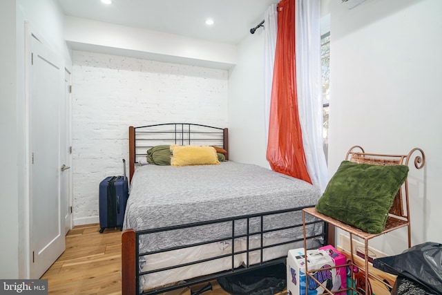 bedroom with brick wall, recessed lighting, and light wood-style flooring