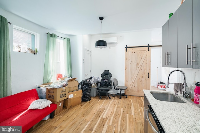 interior space with a wall mounted AC, a barn door, and light wood finished floors