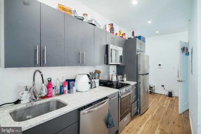 kitchen featuring stainless steel appliances, light wood-style flooring, a sink, recessed lighting, and gray cabinets