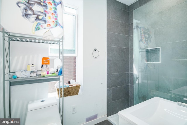 full bath with toilet and a tile shower