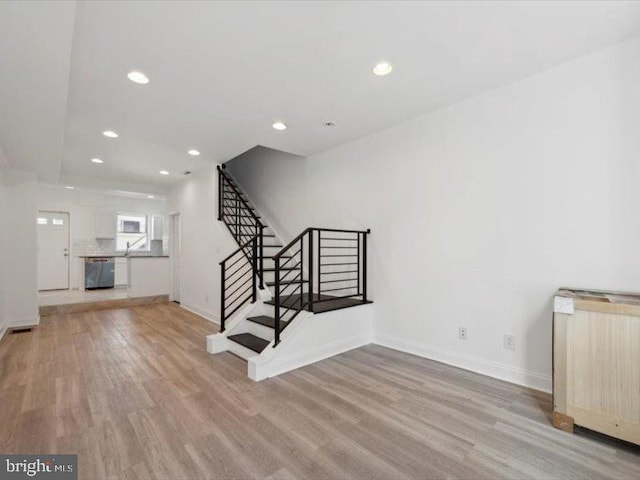 unfurnished living room with sink and light wood-type flooring