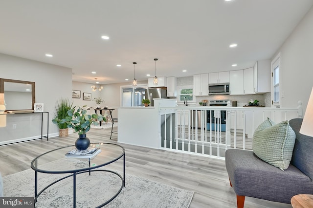 living room with light hardwood / wood-style floors, an inviting chandelier, and sink