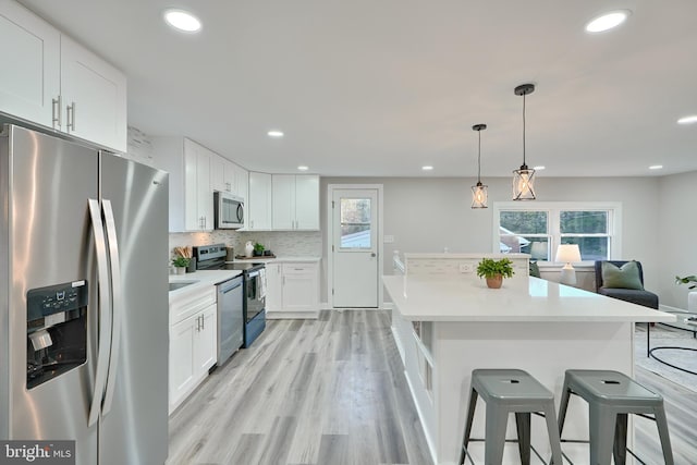 kitchen with a kitchen breakfast bar, white cabinetry, a healthy amount of sunlight, and stainless steel appliances