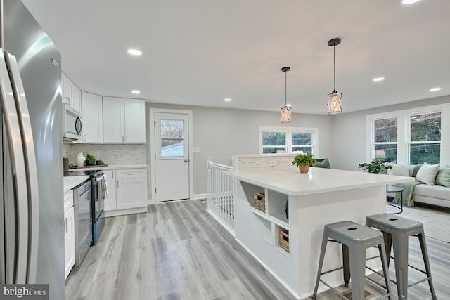 kitchen featuring appliances with stainless steel finishes, decorative backsplash, white cabinetry, and light wood-type flooring