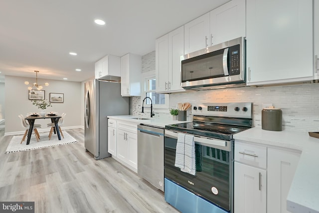 kitchen with light hardwood / wood-style floors, stainless steel appliances, sink, and white cabinets