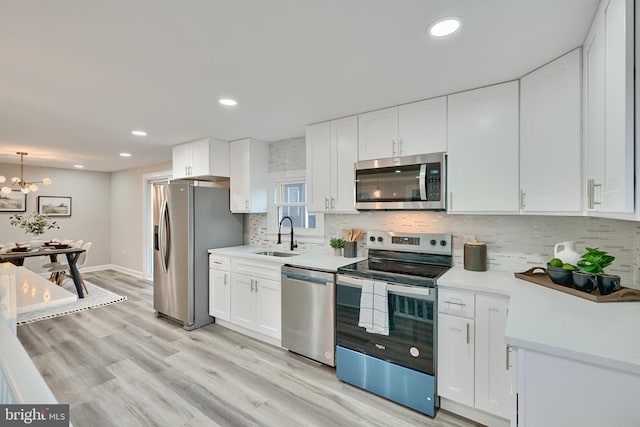 kitchen with light hardwood / wood-style flooring, appliances with stainless steel finishes, sink, and white cabinets