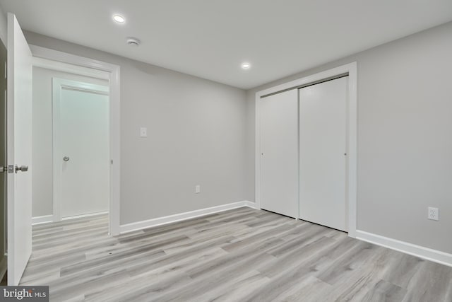 unfurnished bedroom with a closet and light wood-type flooring