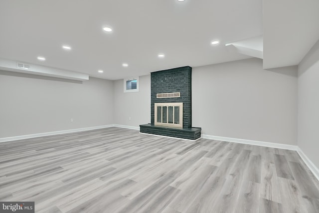 basement with light hardwood / wood-style flooring and a fireplace