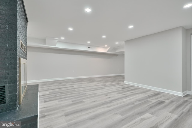 basement featuring light hardwood / wood-style flooring and a fireplace